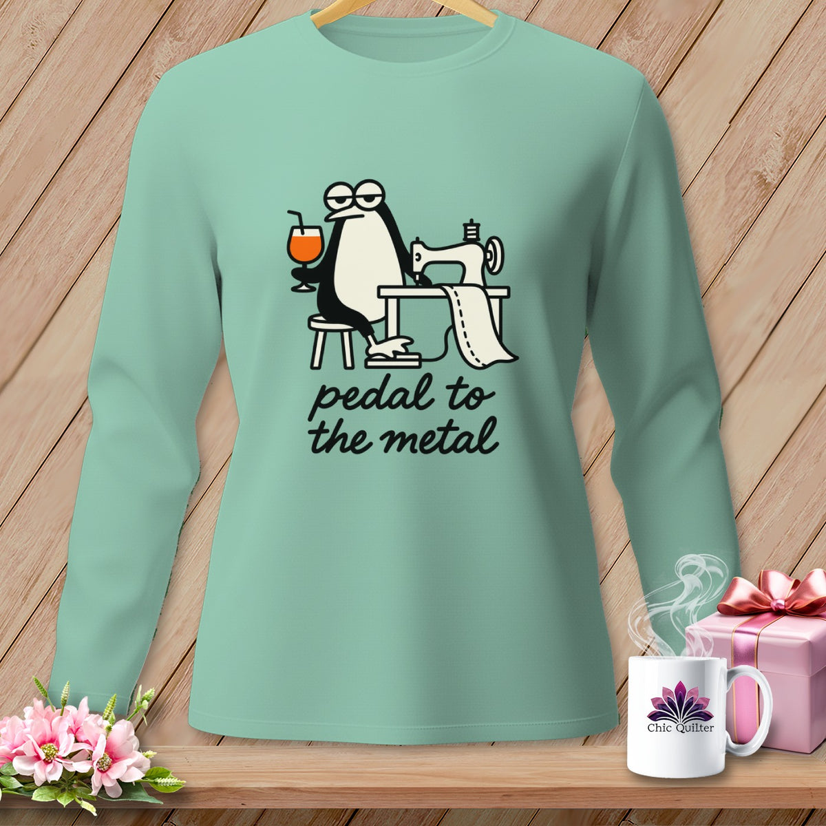 Mint long-sleeve shirt with a penguin sewing and text "pedal to the metal".
