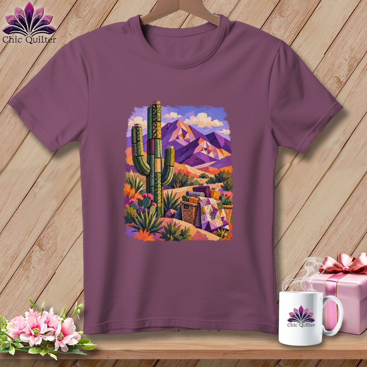 Plum-colored t-shirt featuring a desert landscape graphic with a saguaro cactus, mountains, and rolled quilts.