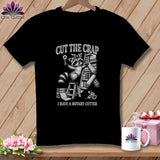 Black t-shirt with a raccoon holding a rotary cutter and fabric rolls.