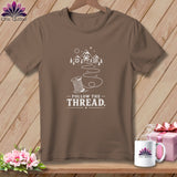 Brown t-shirt with white graphic of spool of thread and 
