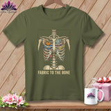 Olive green t-shirt with skeleton filled with fabric and scissors, text reads 