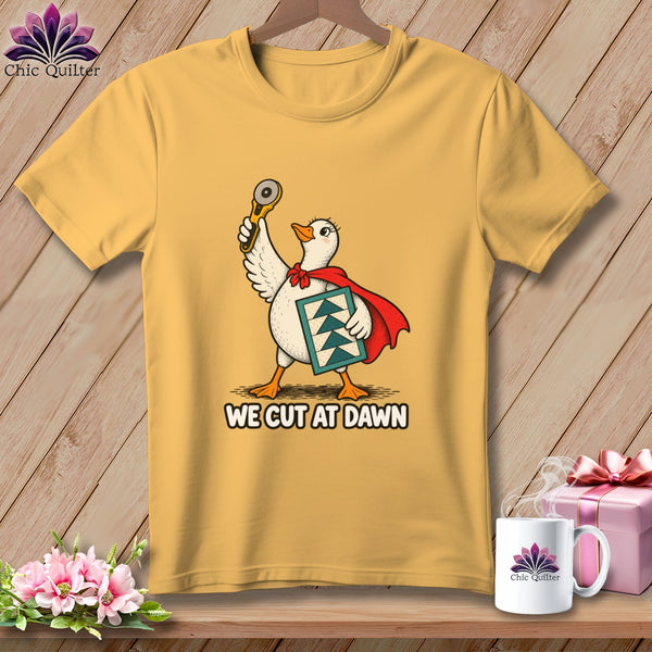 Gold crewneck t-shirt featuring a superhero duck holding a rotary cutter and quilt block, with the text WE CUT AT DAWN.