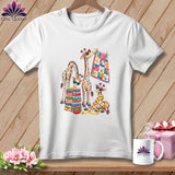 White short-sleeve t-shirt featuring a colorful graphic of giraffes with quilts, glasses, and sewing supplies.