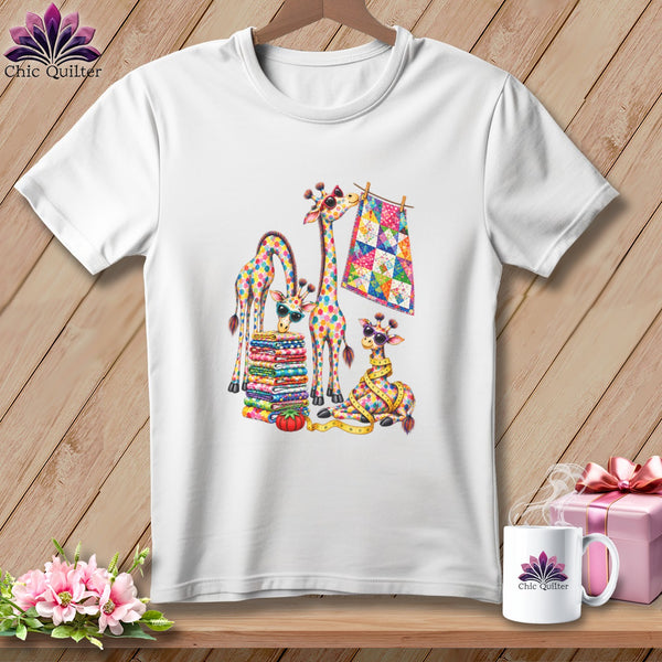 White short-sleeve t-shirt featuring a colorful graphic of giraffes with quilts, glasses, and sewing supplies.
