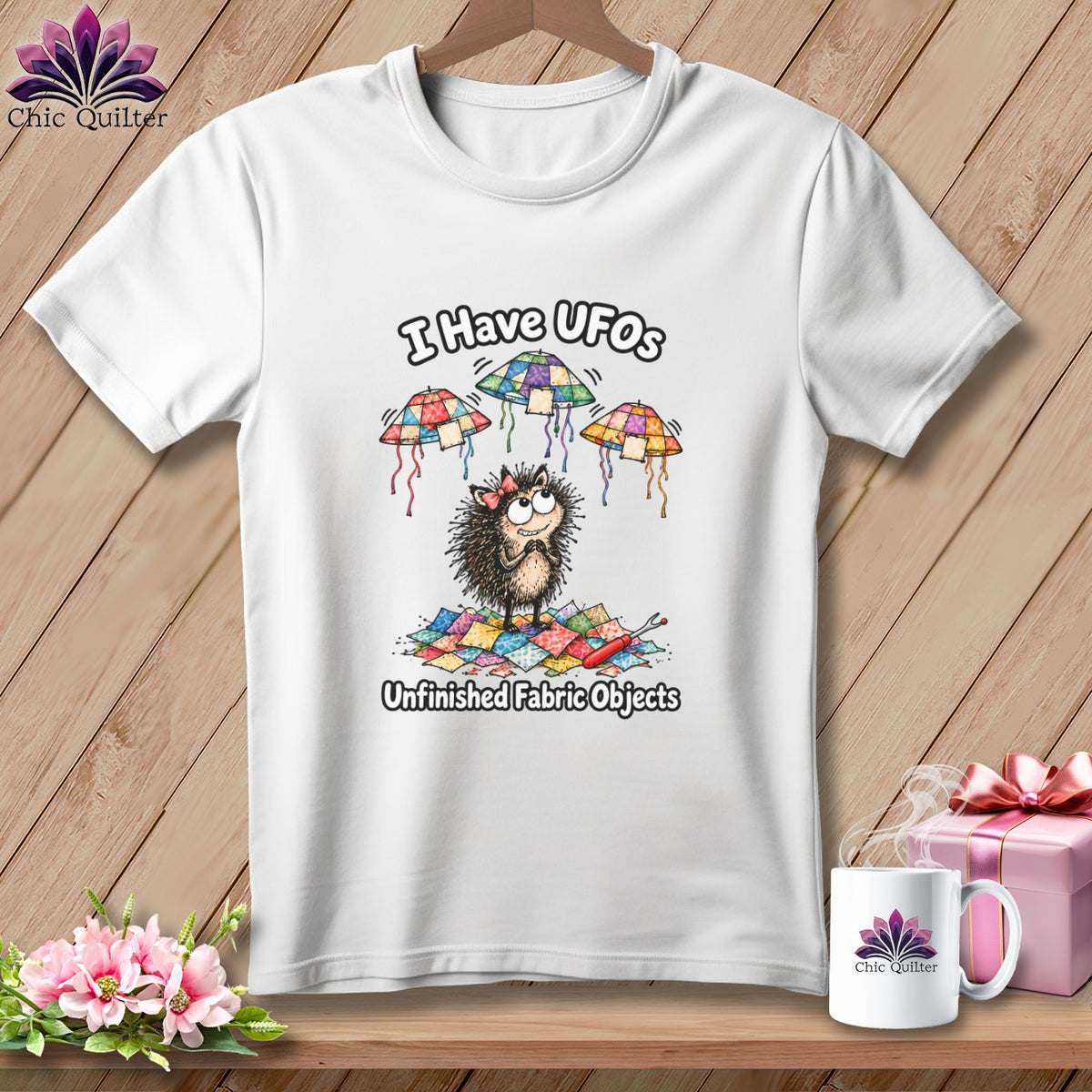 White t-shirt featuring a cartoon hedgehog graphic with patchwork UFOs and the text I Have UFOs Unfinished Fabric Objects.