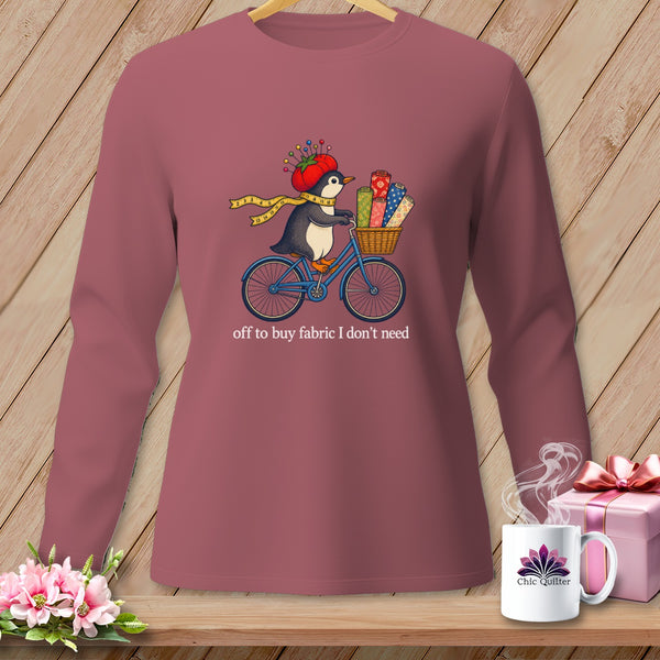 Penguin on a bicycle with fabric rolls in basket, text "off to buy fabric I don't need".