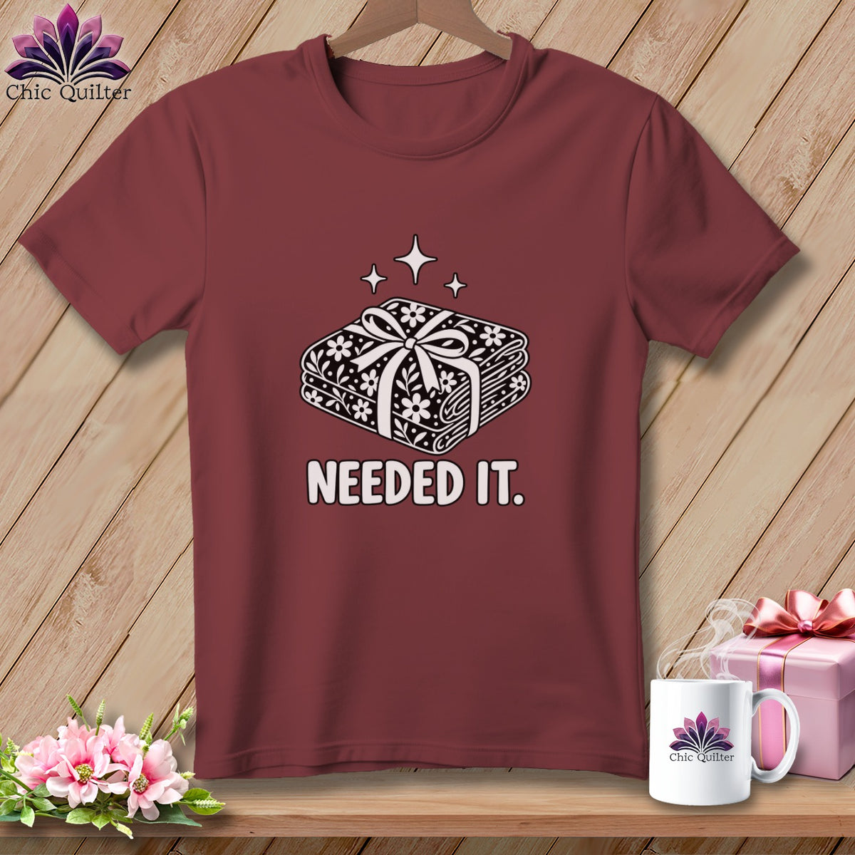 Burgundy t-shirt with a stacked fabric bundle graphic and text "NEEDED IT."