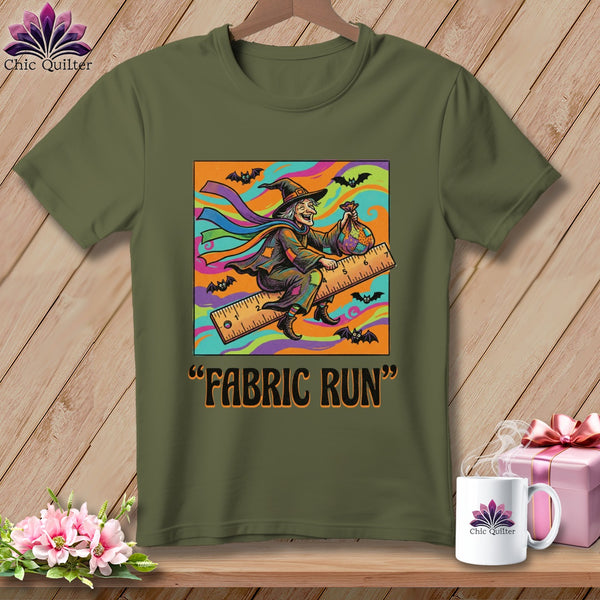 Green t-shirt with a colorful graphic of a witch riding a ruler, bats, and text "FABRIC RUN".