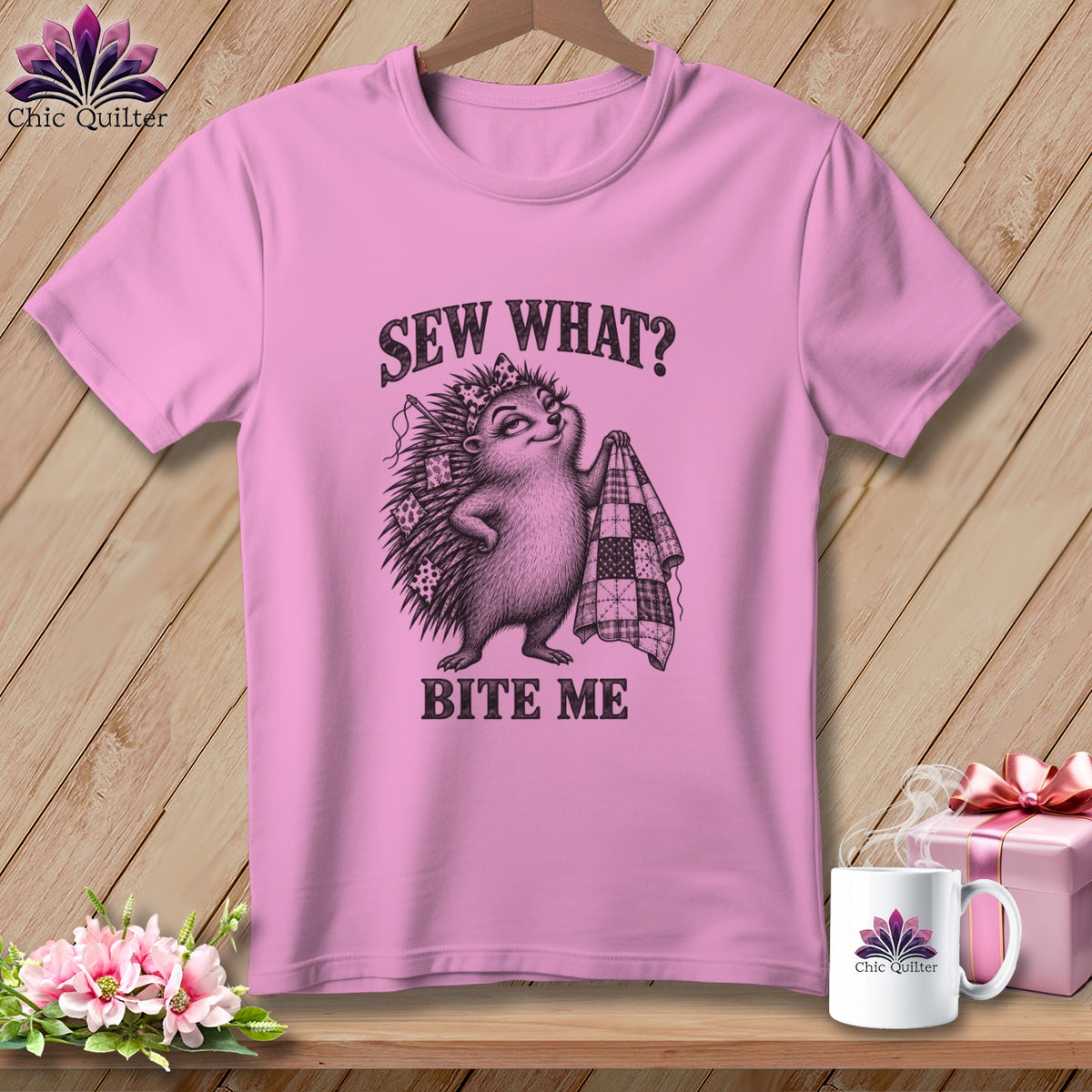 Pink t-shirt with a graphic of a hedgehog holding a quilt and the text Sew What? Bite Me.