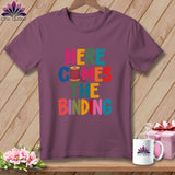 A mauve t-shirt on a wooden hanger with the colorful text 