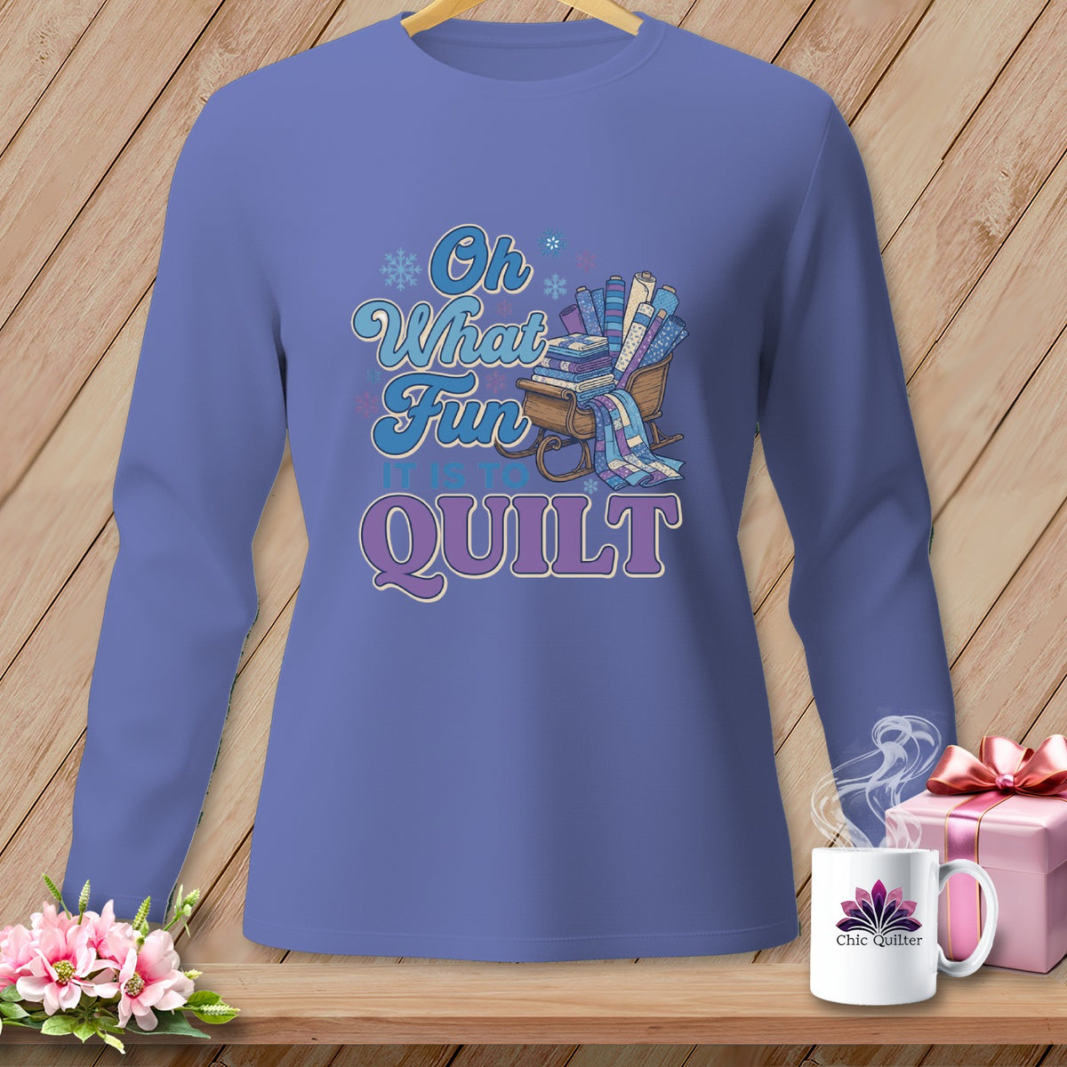 Purple long-sleeve shirt with "Oh What Fun It Is To Quilt" text and a sled of fabric rolls.