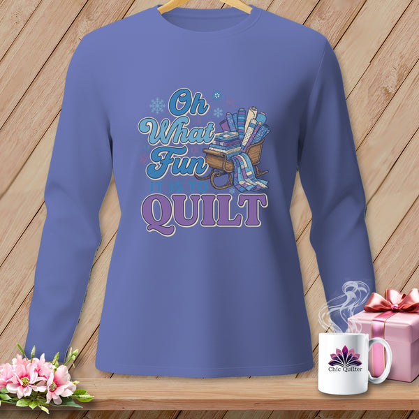 Purple long-sleeve shirt with "Oh What Fun It Is To Quilt" text and a sled of fabric rolls.