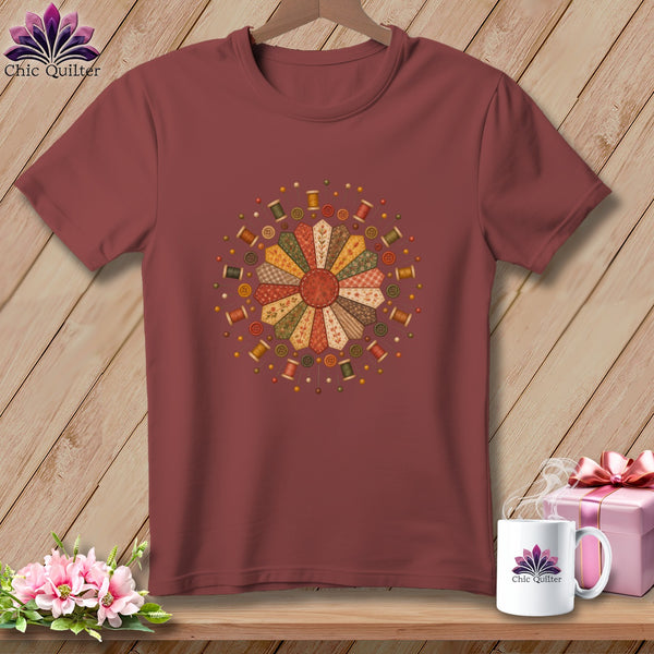 Maroon t-shirt with a circular quilting block design and sewing notions.