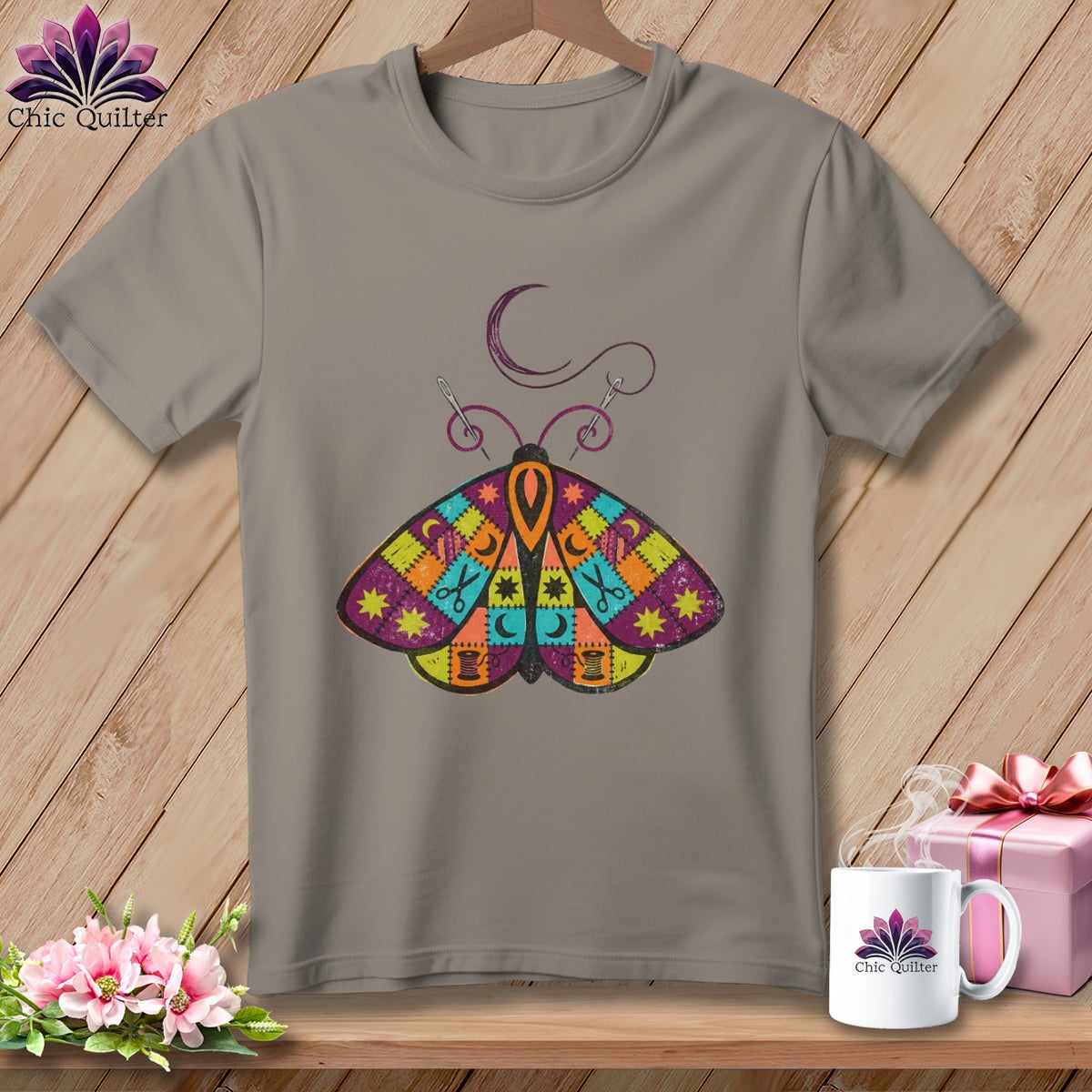 Gray t-shirt with a colorful patchwork moth graphic and sewing-themed elements.