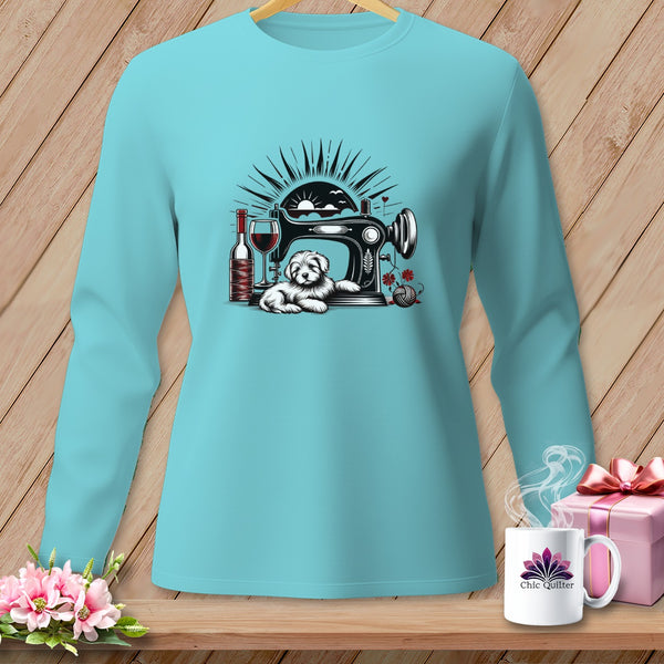 A light blue long-sleeve shirt featuring a graphic of a sewing machine, a puppy, wine, and a sunset.