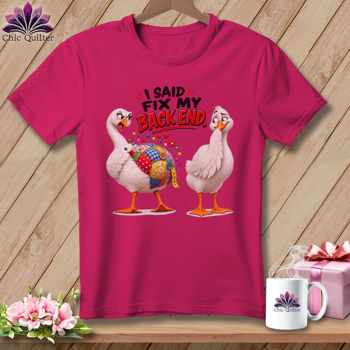 Pink t-shirt with two cartoon geese, one with a patchwork quilt belly. Text reads "I SAID FIX MY BACK END."