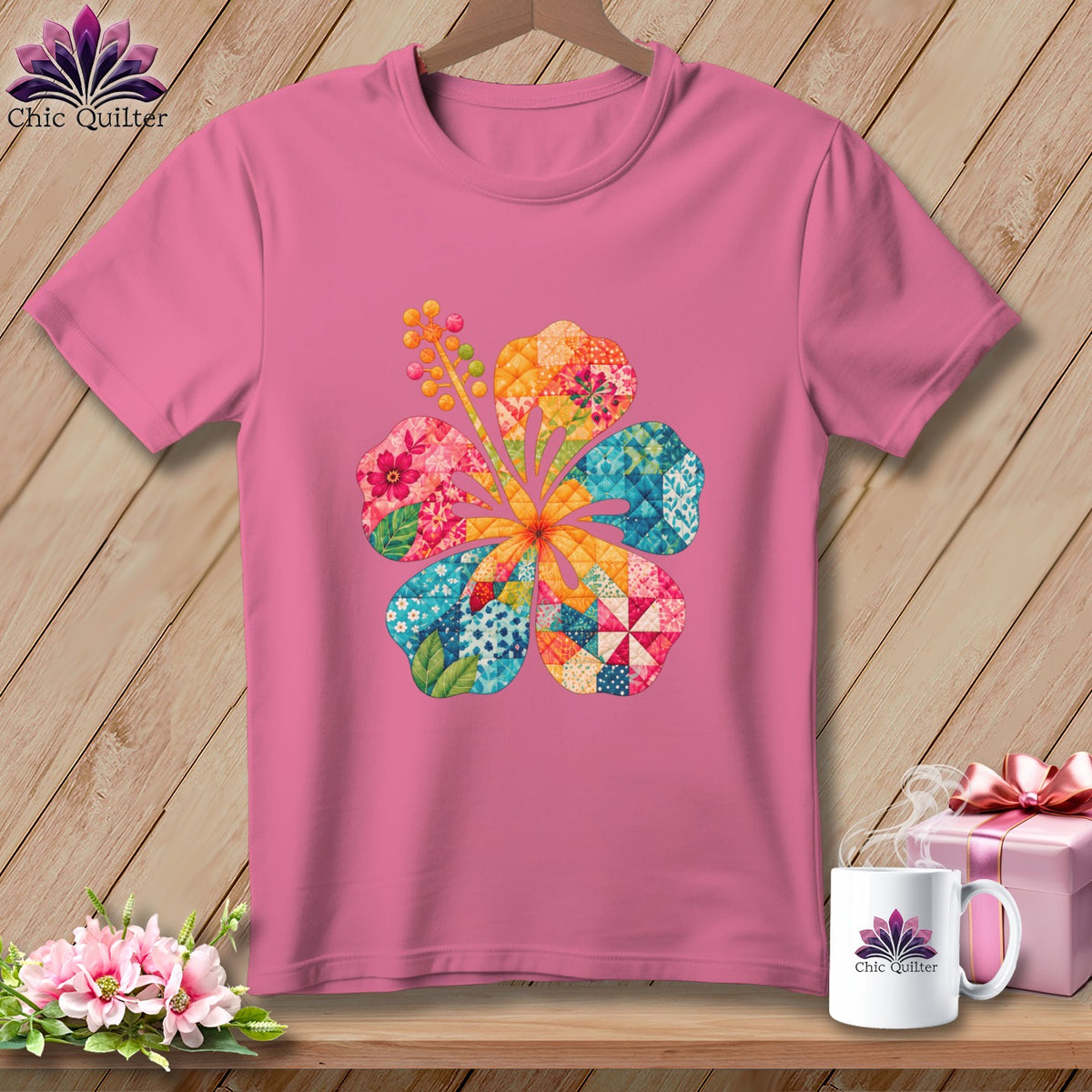 Pink t-shirt with a colorful hibiscus flower graphic on the front, hanging against a wooden wall.
