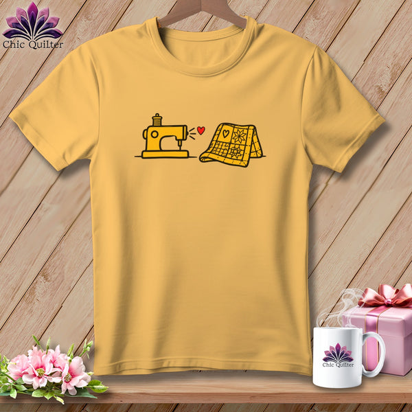Gold crewneck t-shirt featuring a yellow sewing machine and a folded yellow quilt graphic.