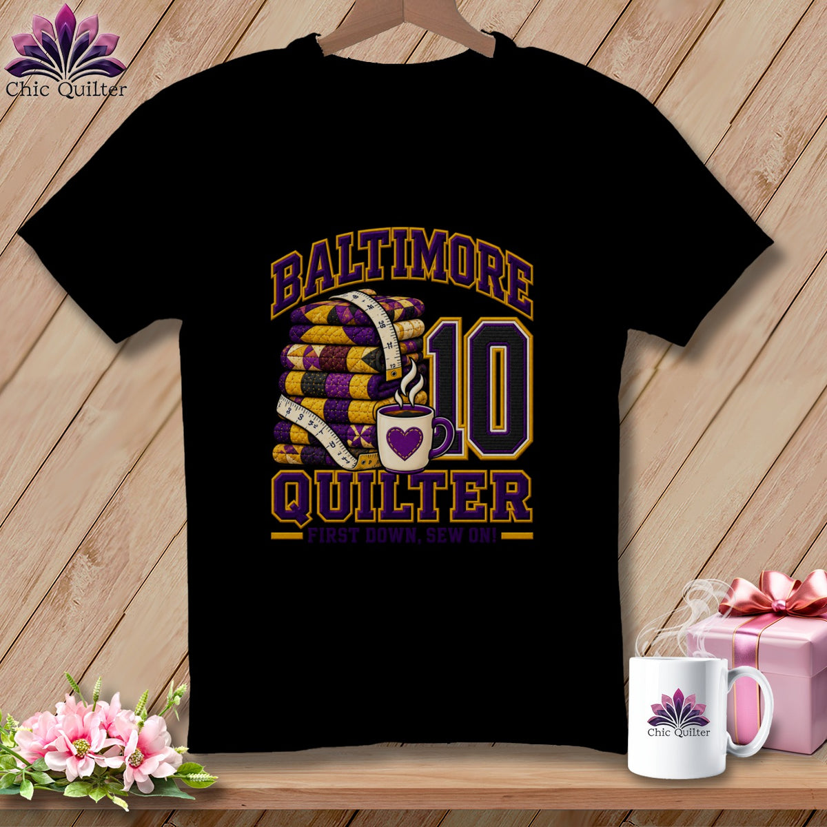 A black short-sleeved t-shirt features a graphic with a stack of purple and yellow quilts, a measuring tape, a coffee mug, the number ten, and text reading Baltimore Quilter and First Down, Sew On!