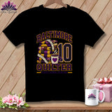 A black short-sleeved t-shirt features a graphic with a stack of purple and yellow quilts, a measuring tape, a coffee mug, the number ten, and text reading Baltimore Quilter and First Down, Sew On!