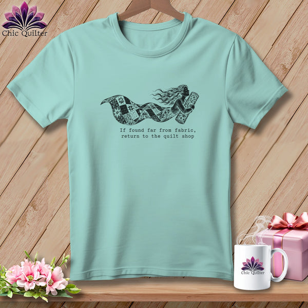Teal t-shirt with a mermaid made of quilt fabric and the text "If found far from fabric, return to the quilt shop."