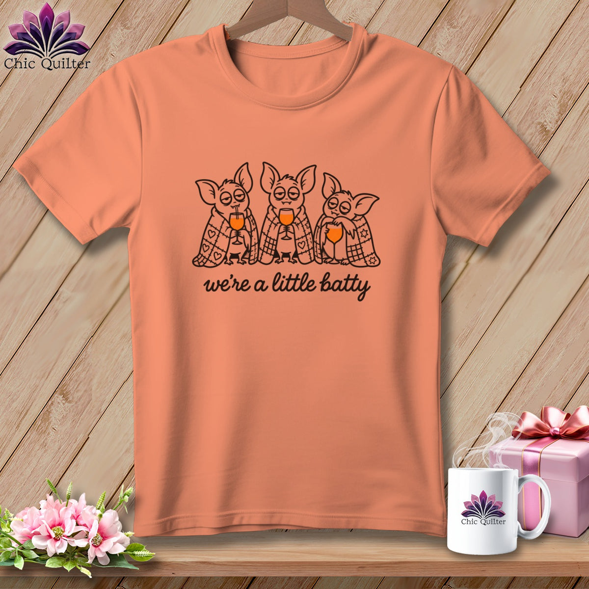 Peach t-shirt with three bats drinking wine and text "we're a little batty".