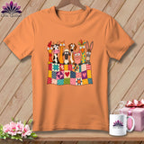 An orange t-shirt displays a graphic of cartoon farm animals peeking over a colorful patchwork quilt.