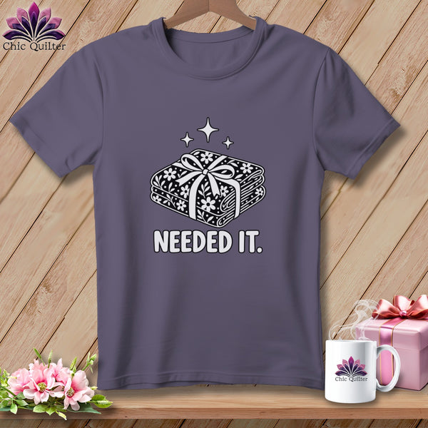 Purple t-shirt with a graphic of folded fabric and the text "NEEDED IT."