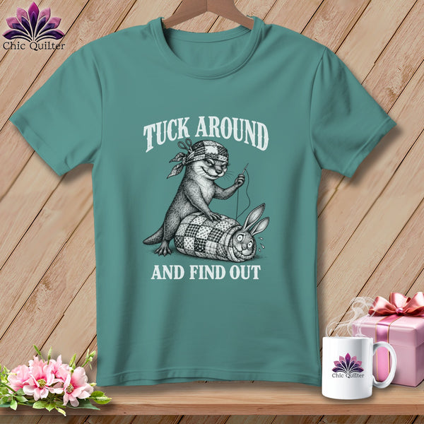 Teal crewneck t-shirt featuring a graphic of an otter sewing a rabbit into a patchwork quilt with the text TUCK AROUND AND FIND OUT.