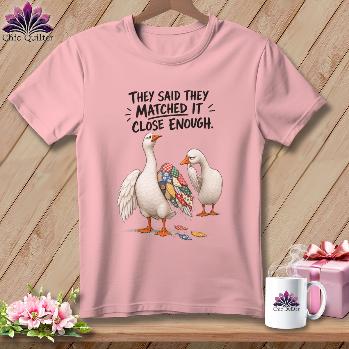 Pink t-shirt with two geese, one with a patchwork wing, and text "They said they matched it = close enough."