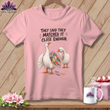 Pink t-shirt with two geese, one with a patchwork wing, and text 