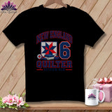 A black t-shirt featuring a New England Quilter graphic with a quilt block, number six, and sewing tools.