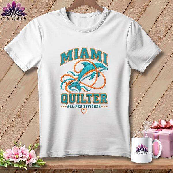 A white t-shirt features a dolphin graphic with the text MIAMI QUILTER against a wooden background.