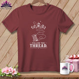 Maroon t-shirt with white design of a spool of thread and 