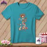 Teal short-sleeved t-shirt featuring a cartoon graphic of a woman holding a quilt block and a stack of fabrics, with a cat sitting beside her.