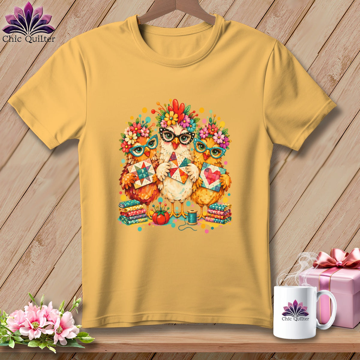 A yellow crewneck t-shirt featuring a colorful graphic of three chickens wearing glasses and floral crowns while holding quilted blocks.