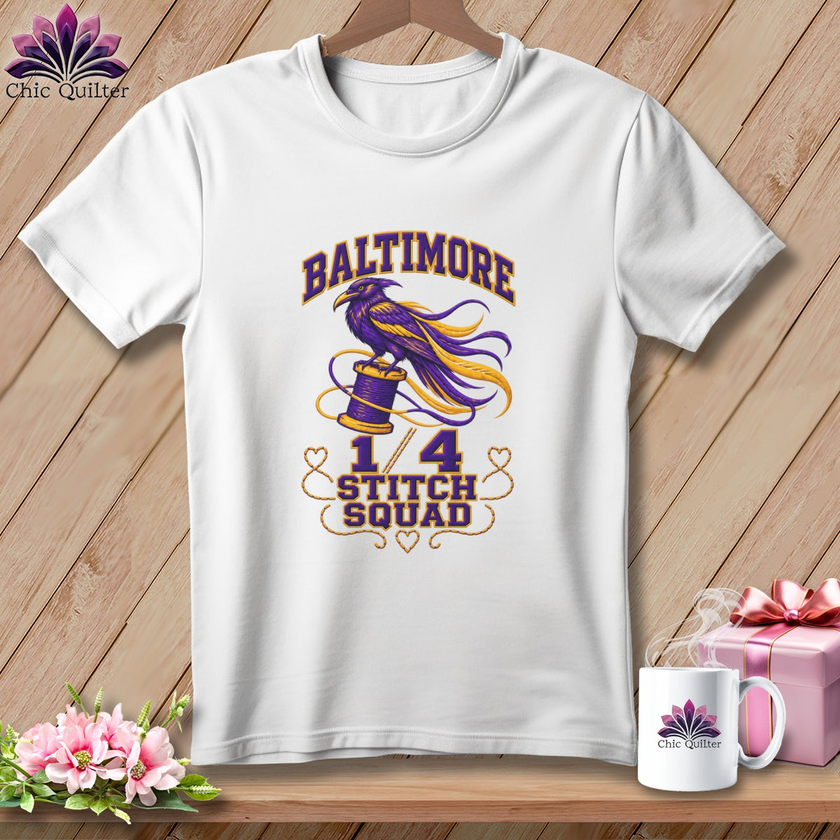 A white crewneck t-shirt featuring a purple and yellow graphic with a raven, spool of thread, and text reading Baltimore Stitch Squad.