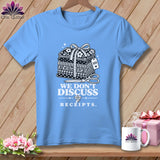 Light blue t-shirt with graphic of stacked fabric, scissors, and text 