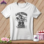 A white t-shirt hanging on a wooden wall displays a graphic of a pirate bird holding a spool of thread beneath text reading "Las Vegas 99 Stash League."
