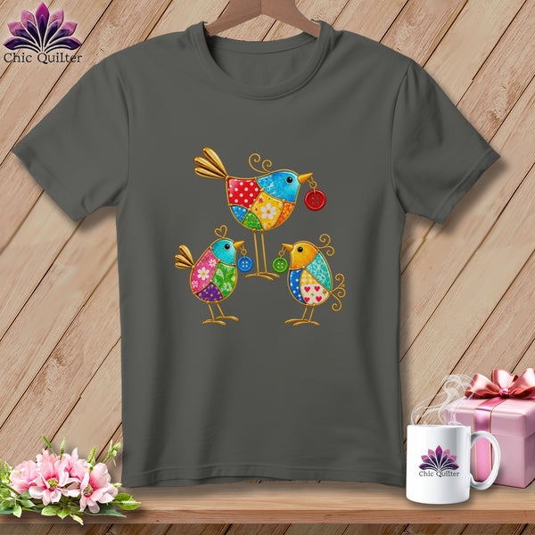 A dark gray t-shirt with a graphic of three colorful patchwork birds holding buttons.