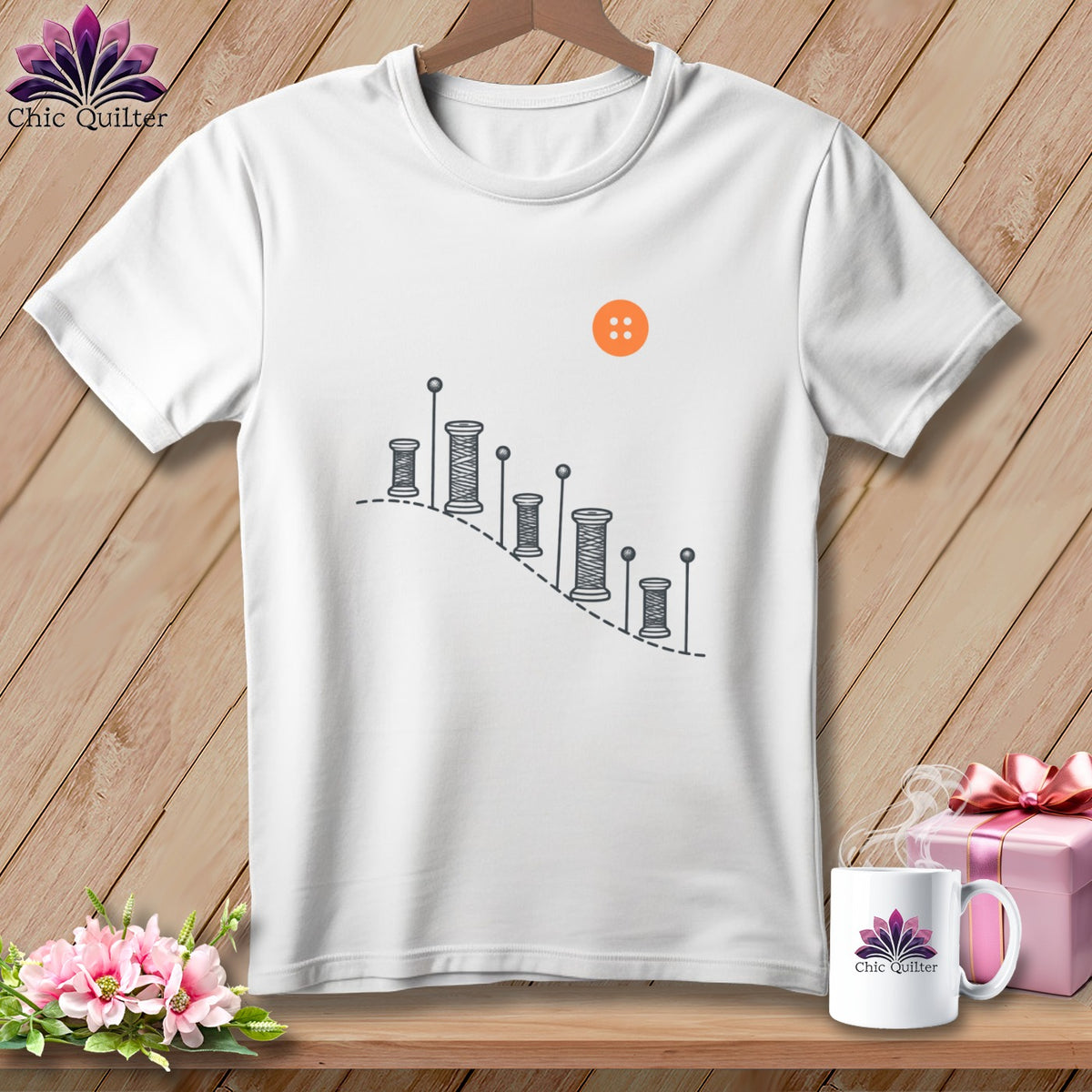 White t-shirt with sewing thread spools, pins, and orange button graphic.