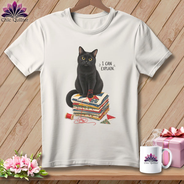 Black cat sits on quilt squares with thread, saying "I CAN EXPLAIN."