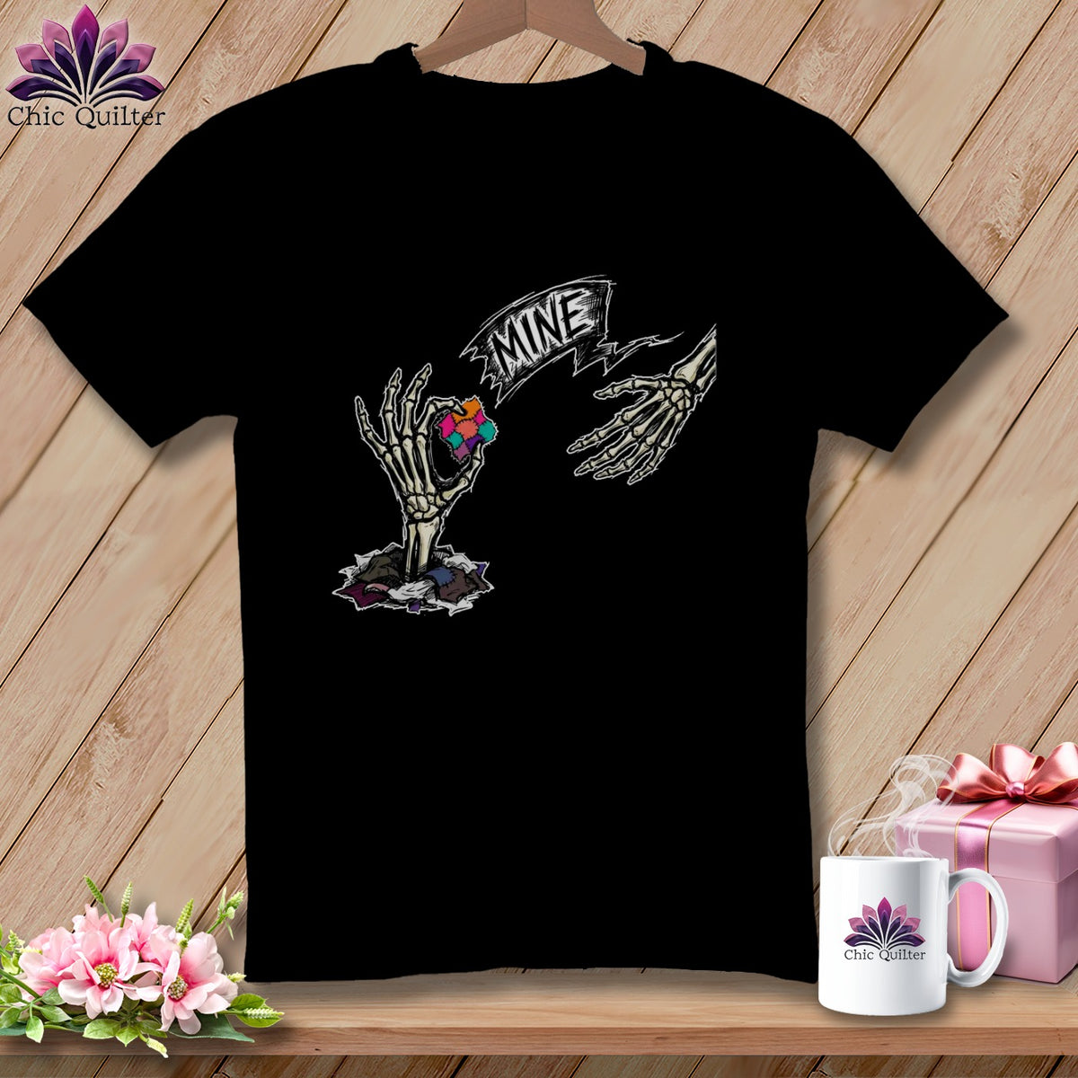 Black t-shirt with skeleton hands holding a colorful quilt piece and banner saying "MINE".