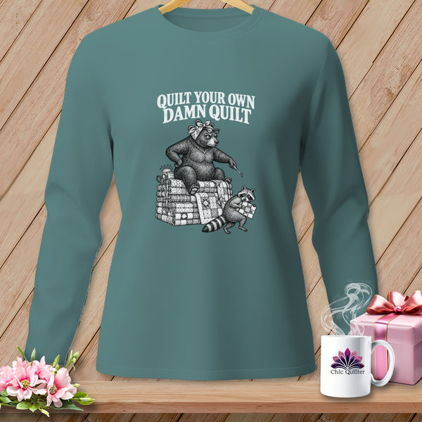Teal long-sleeve t-shirt with a vintage illustration of a bear and raccoon quilting and the text Quilt Your Own Damn Quilt.