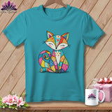 Teal crewneck t-shirt featuring a colorful patchwork fox graphic, hanging against a wooden background.