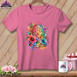 A pink t-shirt on a wooden background features a colorful watercolor thimble graphic surrounded by flowers.