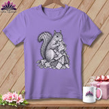 A purple crewneck t-shirt features a black and white illustration of a squirrel holding patterned quilt squares.
