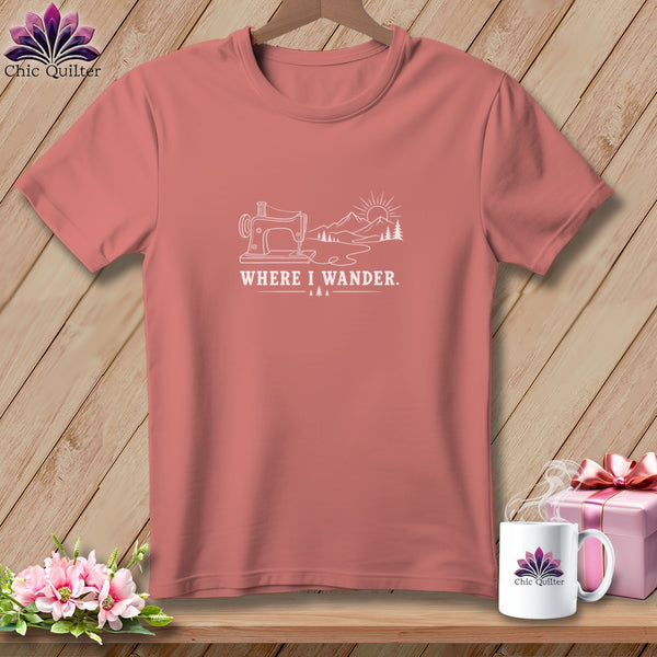 Pink t-shirt with white line art of sewing machine, mountains, sun, and trees. Text reads "WHERE I WANDER."