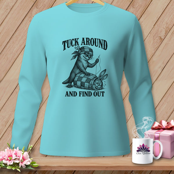 Light blue long-sleeve shirt with an otter sewing a rabbit into a quilt, featuring the text TUCK AROUND AND FIND OUT.
