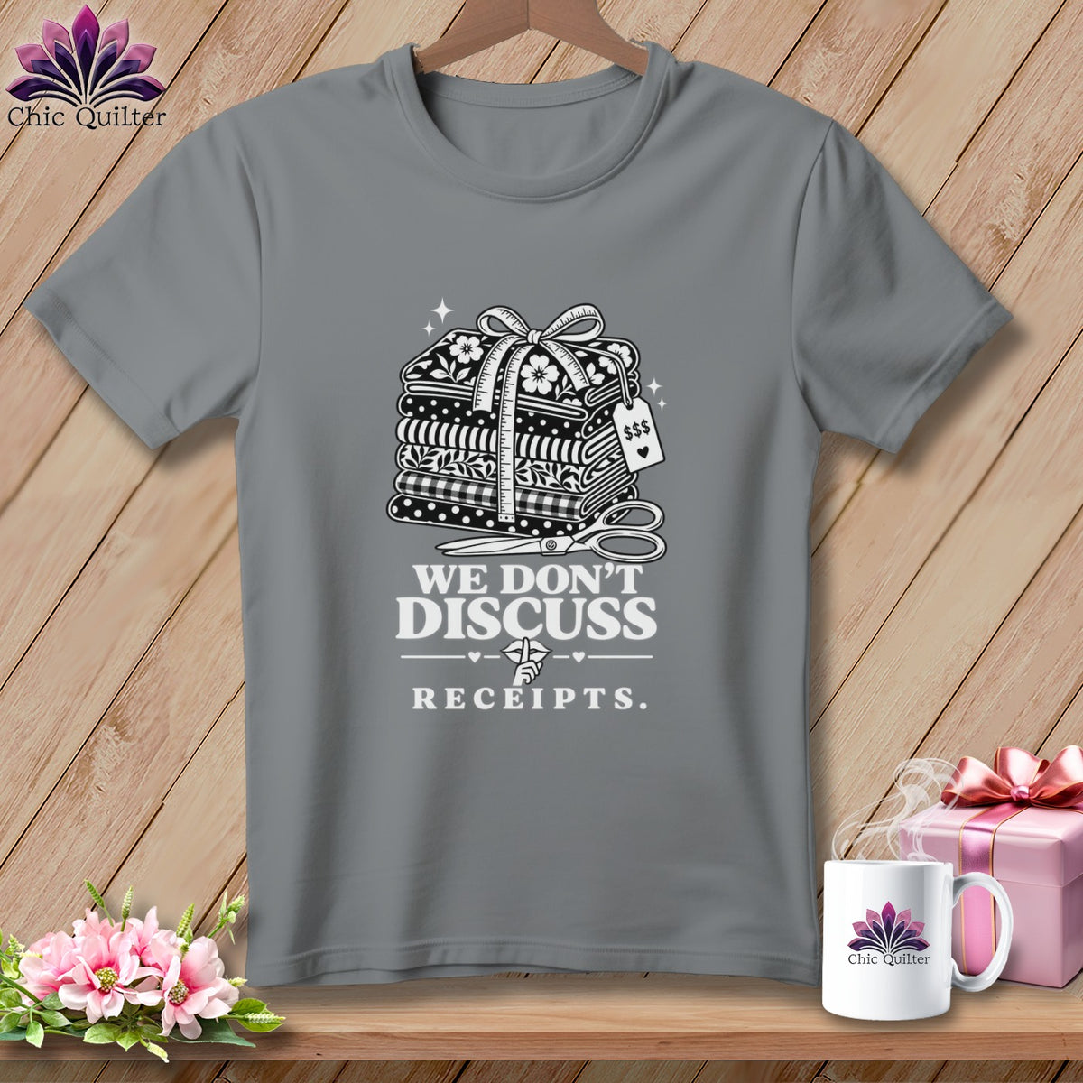 Grey t-shirt with stacked fabric, scissors, and text "WE DON'T DISCUSS RECEIPTS."
